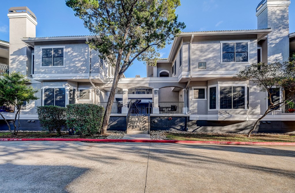 a white house with a sidewalk and trees in front of it