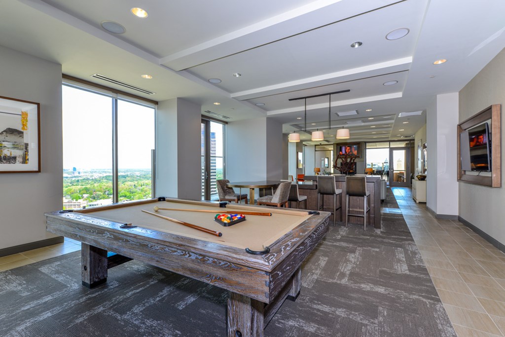 a game room with a pool table and a view of the living room and dining