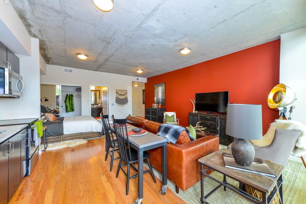 a living room with an orange accent wall and a dining room table