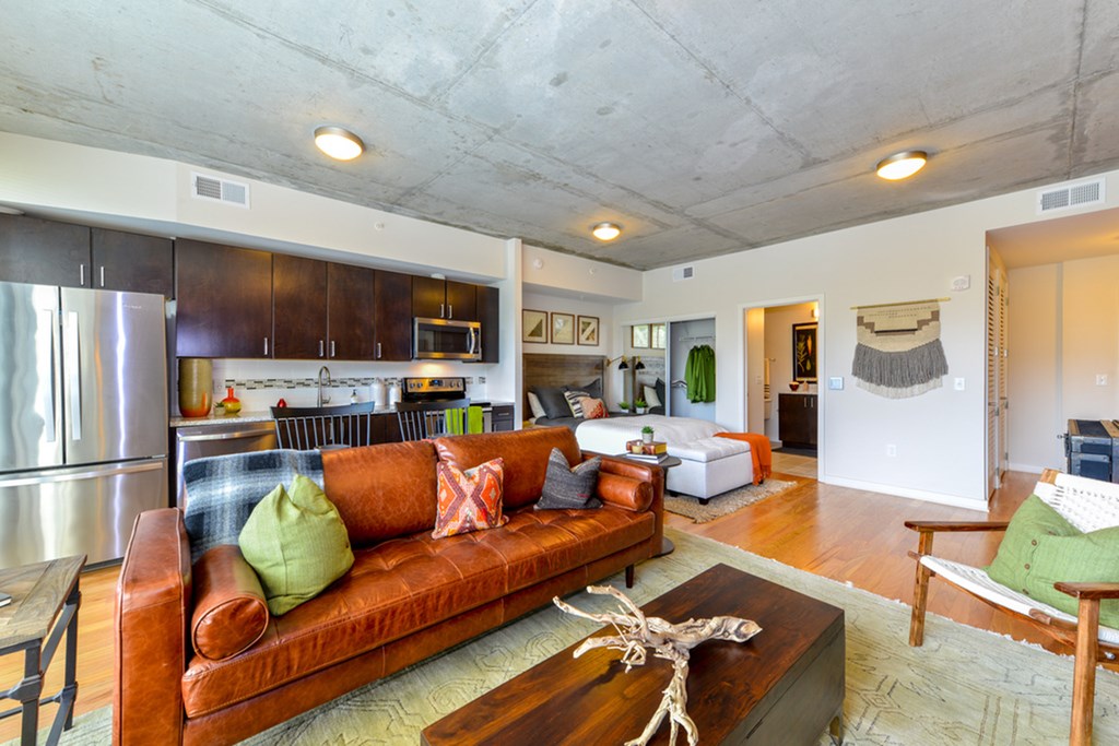a living room with a brown leather couch and a kitchen