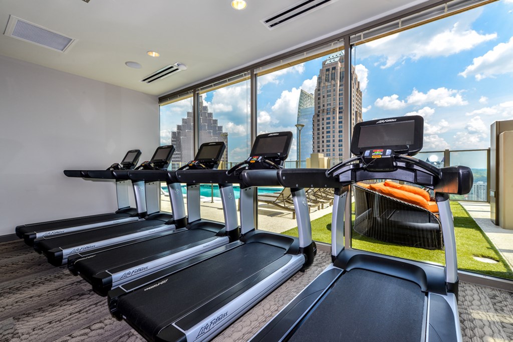 a gym with cardio machines and a view of the city