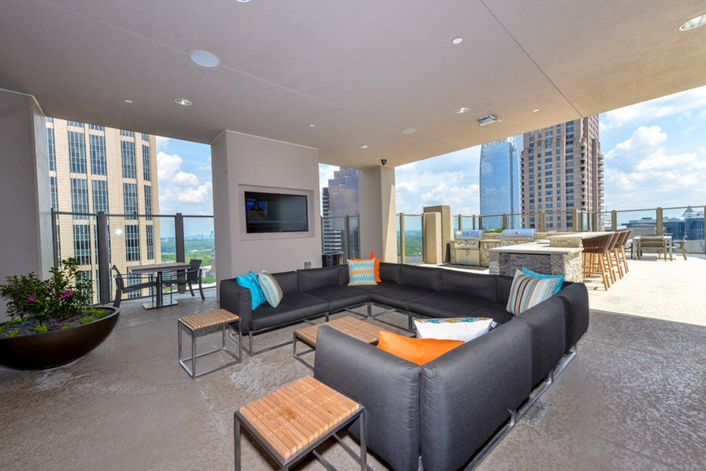 a living room with black couches and a television and a view of the city