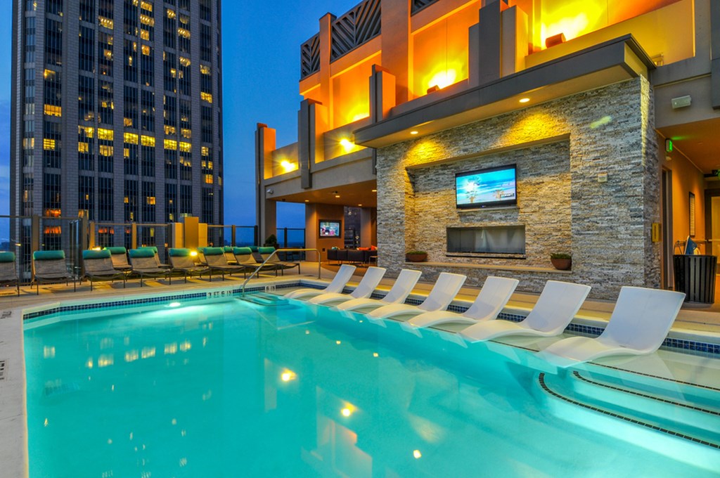 a swimming pool with lounge chairs in front of a building