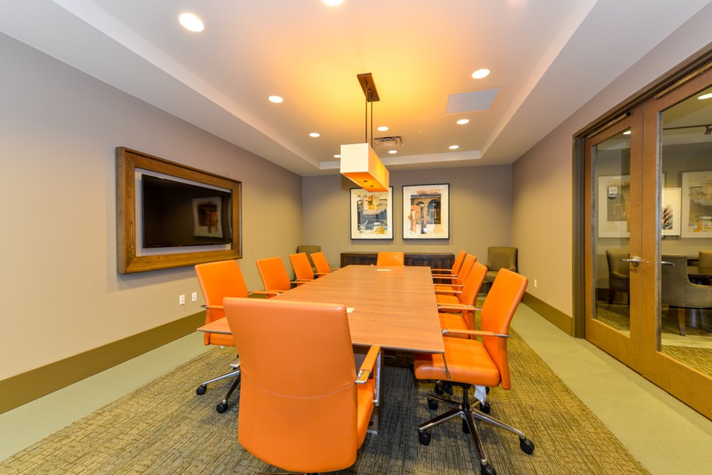 a conference room with a wooden table and orange chairs