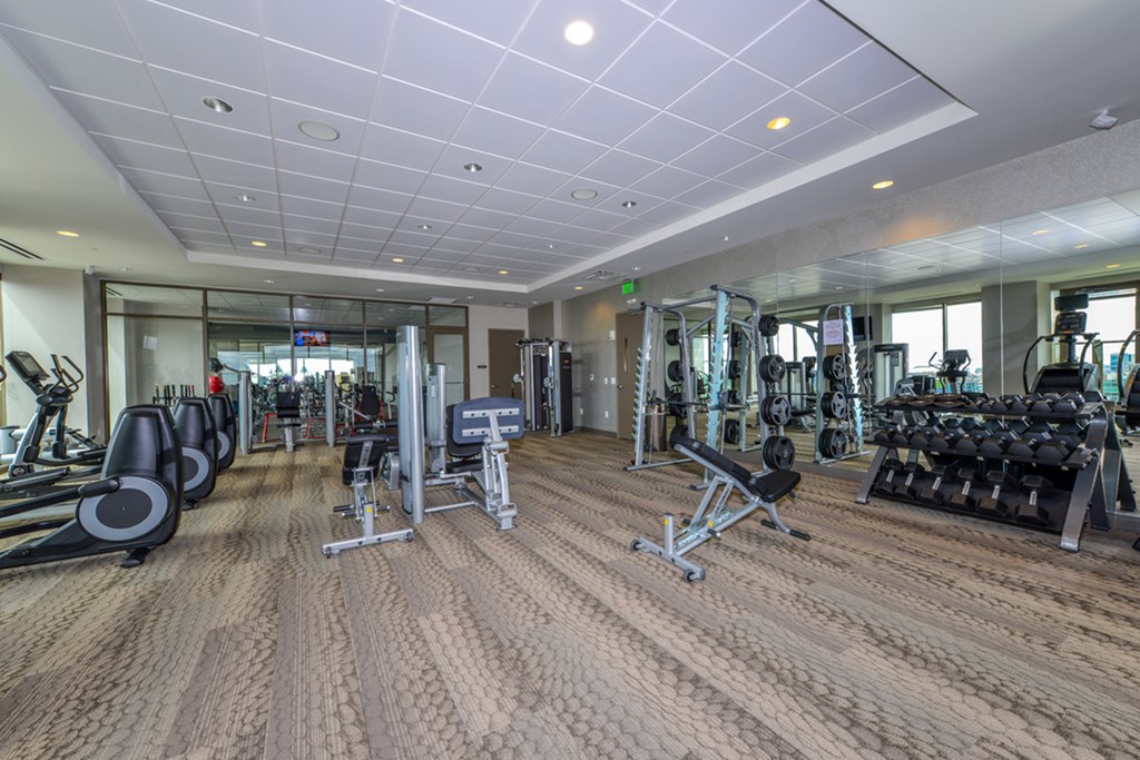 a gym with weights and cardio equipment in a building with glass walls