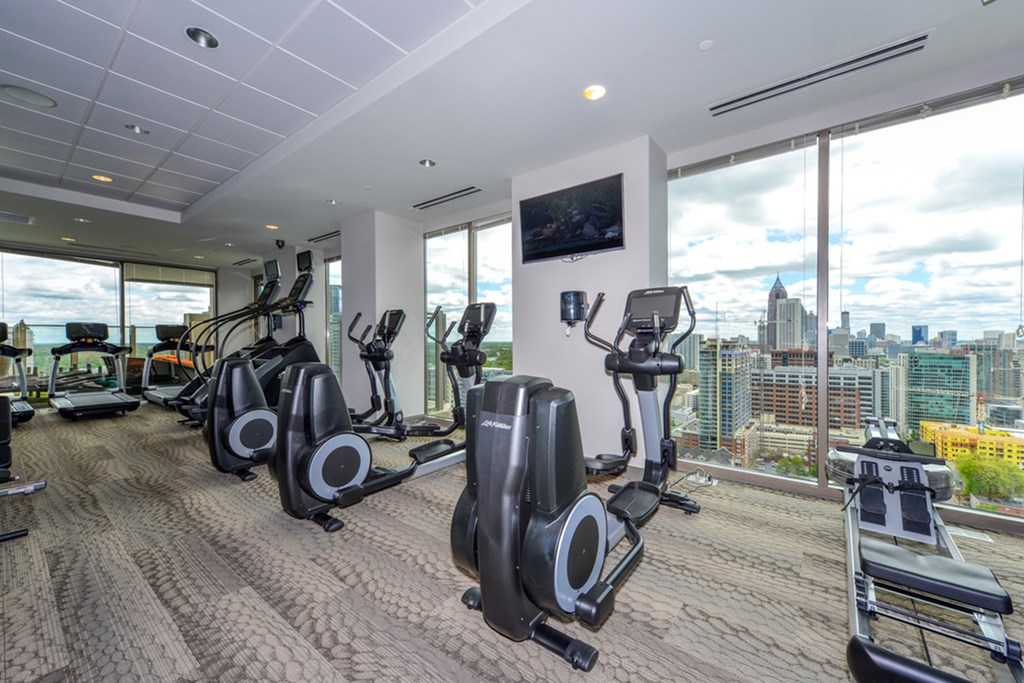 a gym with cardio machines and a view of the city
