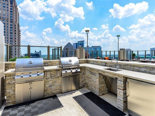 a rooftop kitchen with stainless steel appliances and a city in the background