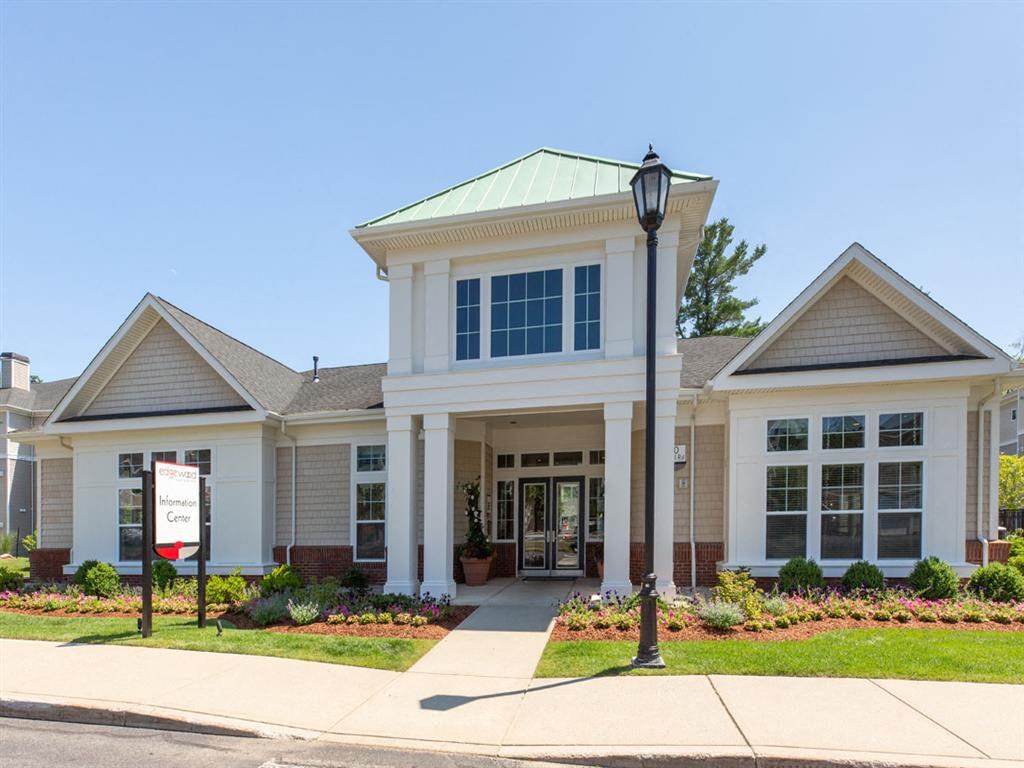 the front of a white house with a sign on the sidewalk