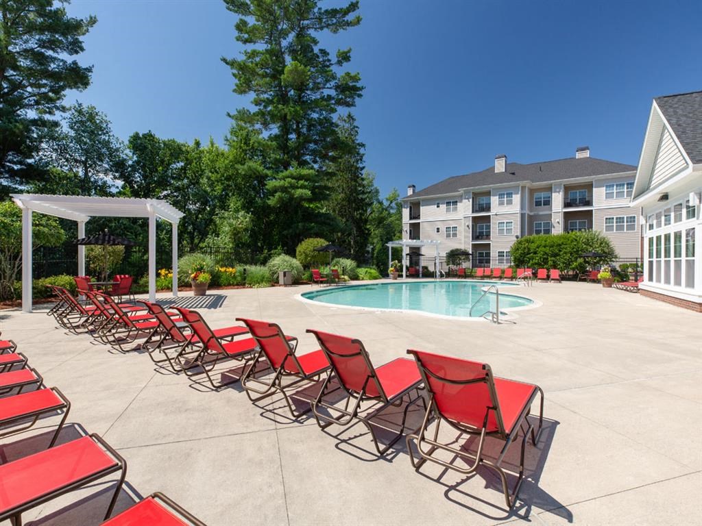 our apartments have a large pool with red chairs