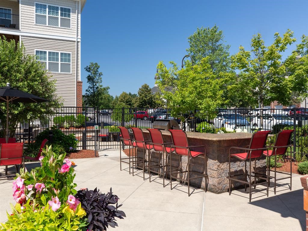 a patio with a bar and chairs in front of a building