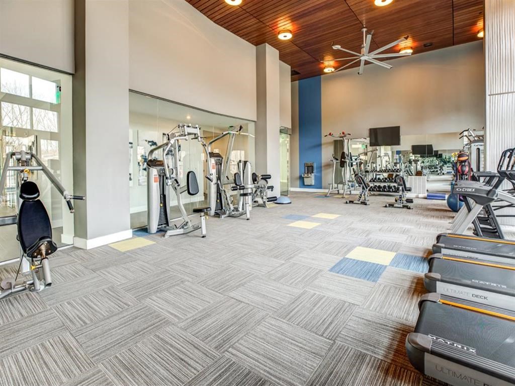 a gym with cardio equipment and weights in a building with windows