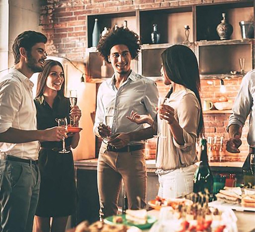 a group of people standing in a kitchen holding wine glasses