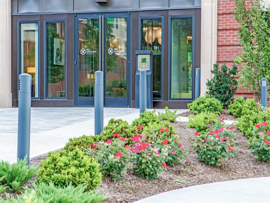 a flower garden in front of a building with glass doors