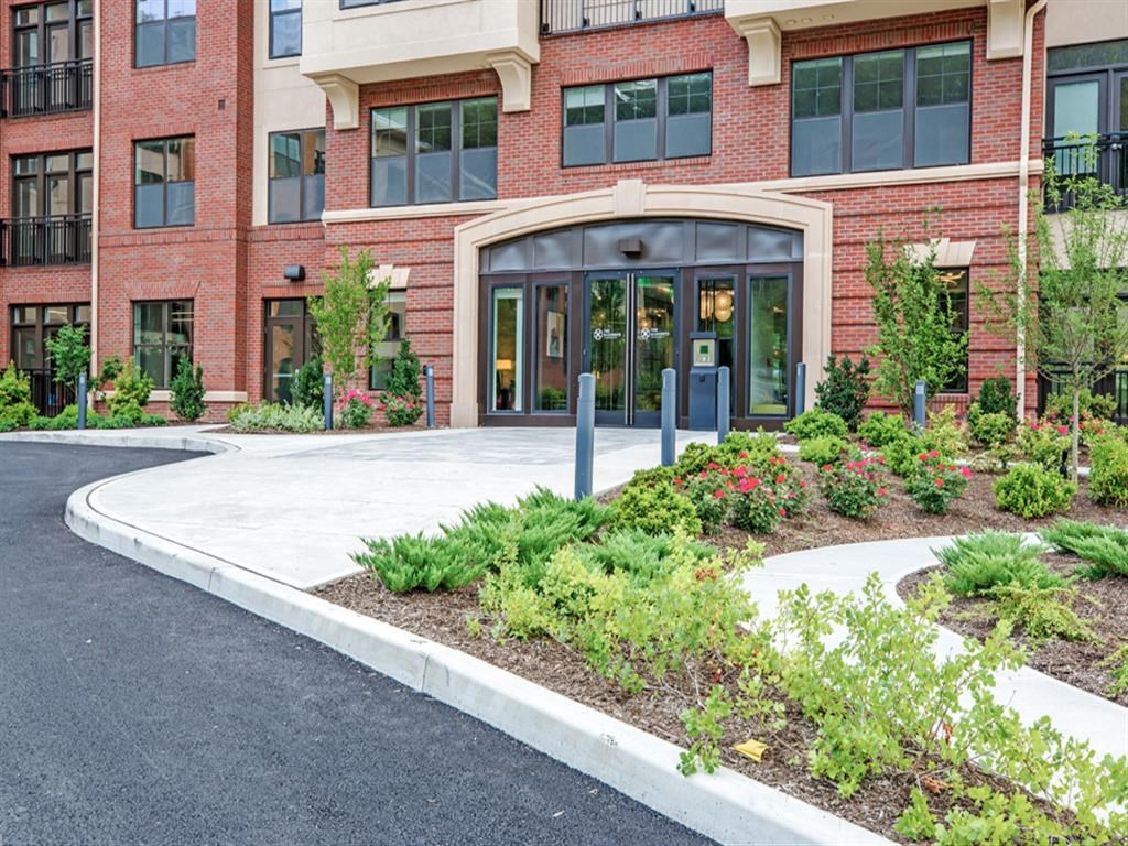 the entrance to a building with a sidewalk and landscaping