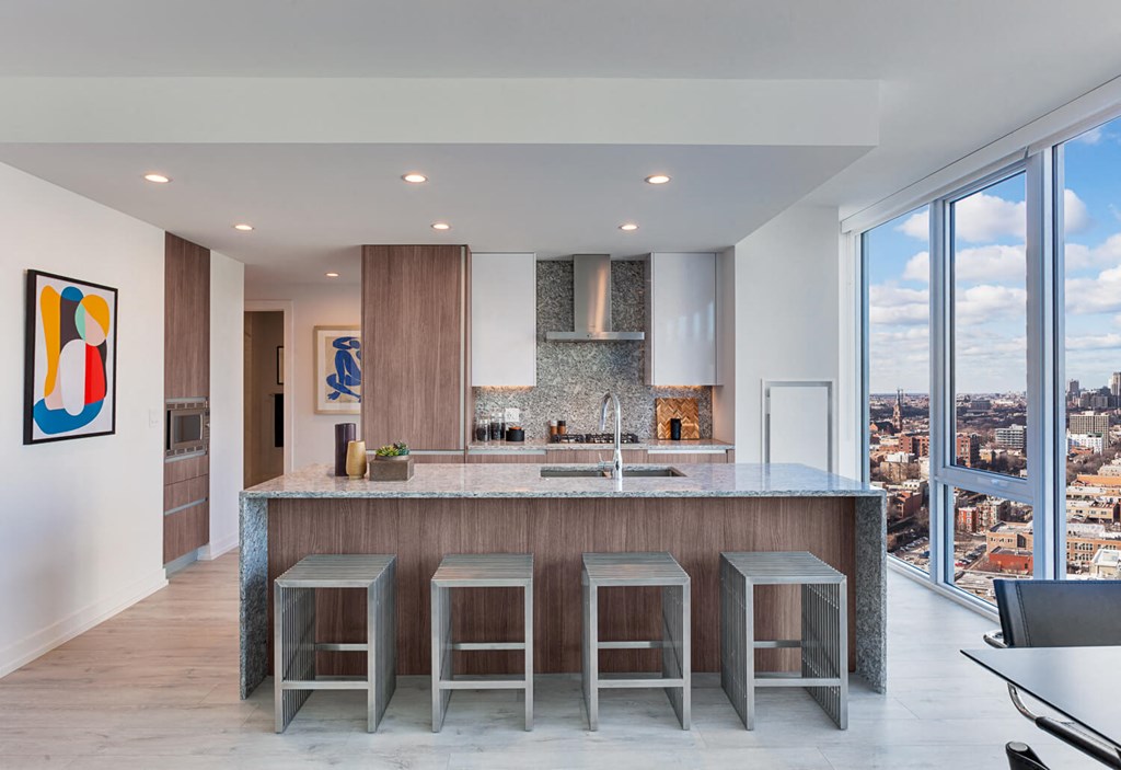 a kitchen with an island and three stools in front of a window