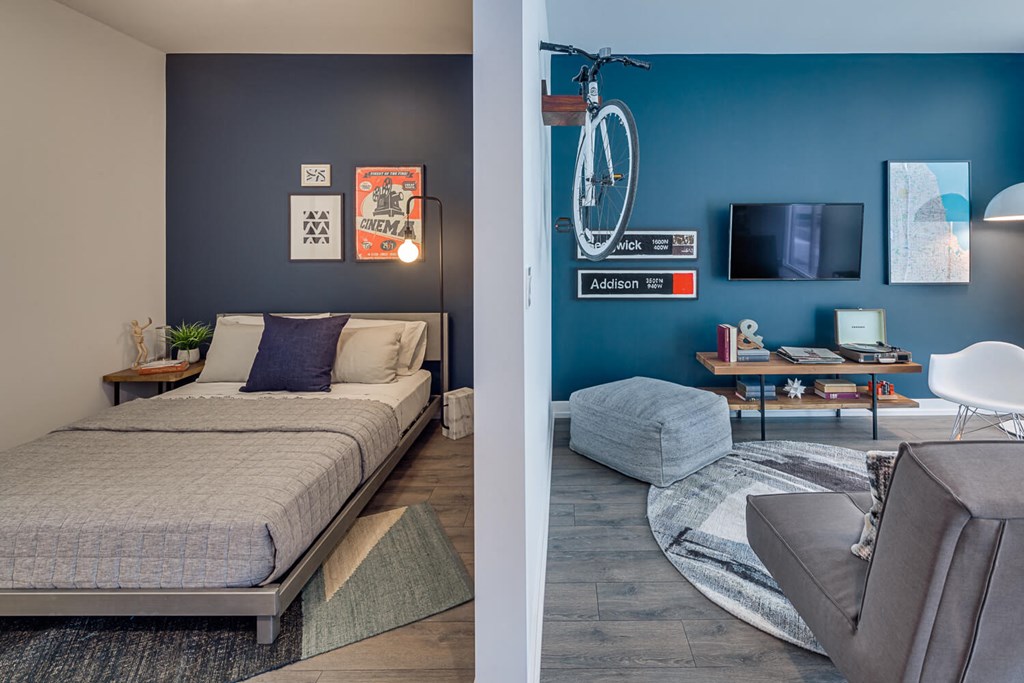 a bedroom and a living room with a bed and a bike on the wall