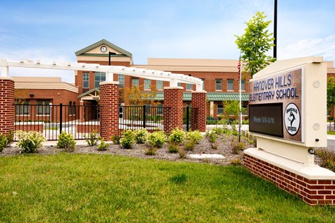 the front of a school with a sign and a fence