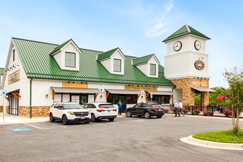 a supermarket with a clock tower and cars parked in front
