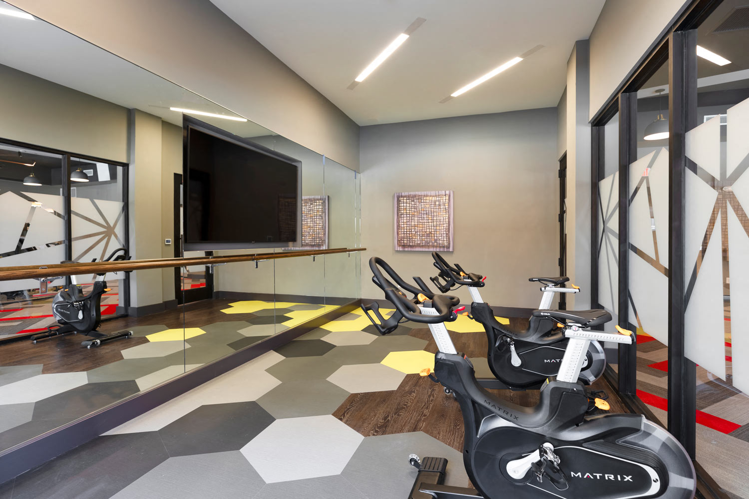 a workout room with exercise bikes and a tv