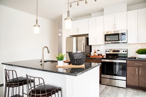 a kitchen with white cabinets and black counter tops