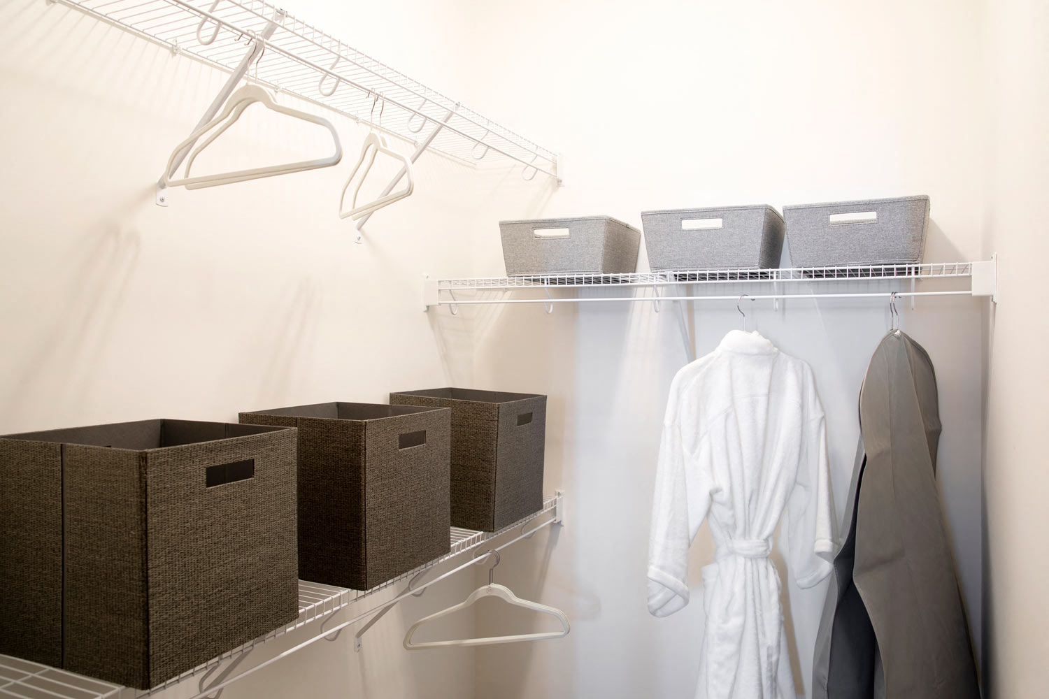 a white closet with baskets and a rack with clothes