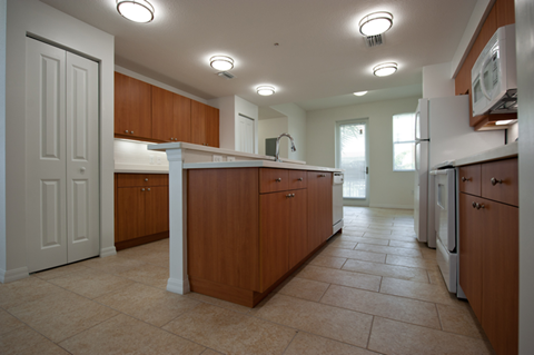 a kitchen with wooden cabinets and white appliances and a tile floor