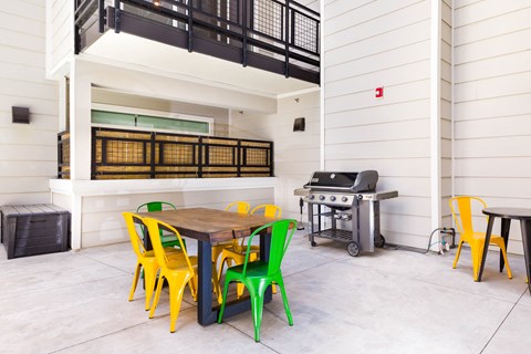 a patio with a table and chairs and a grill