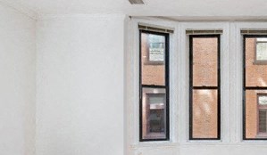 an empty living room with windows and wooden floors