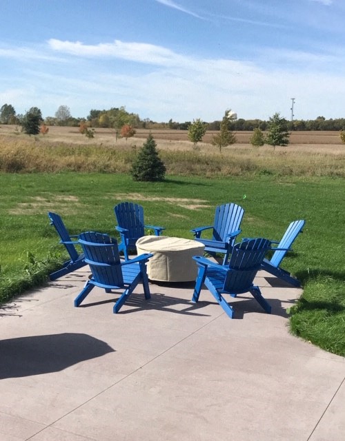 a patio with blue chairs and a fire pit
