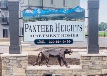 a statue of a dog in front of the panther heights apartment homes sign