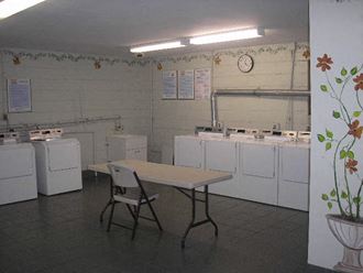 an empty room with white washing machines and a table