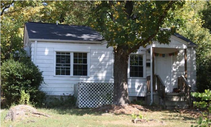 a small white house with a tree in front of it