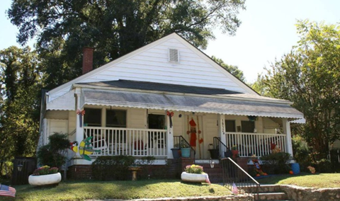 A white house with a porch and a flag on it.