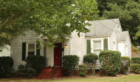 a small white house with a red door