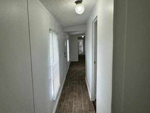A long, narrow hallway with a light on the ceiling and a door at the end.
