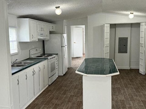 A kitchen with white cabinets and a green table top.