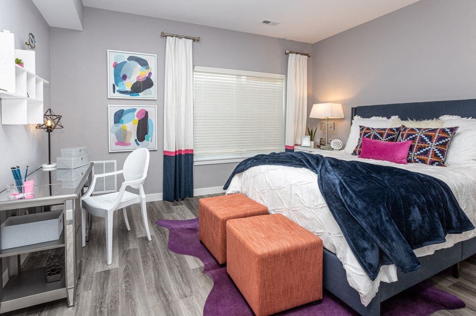 a bedroom with a bed and a desk and a window