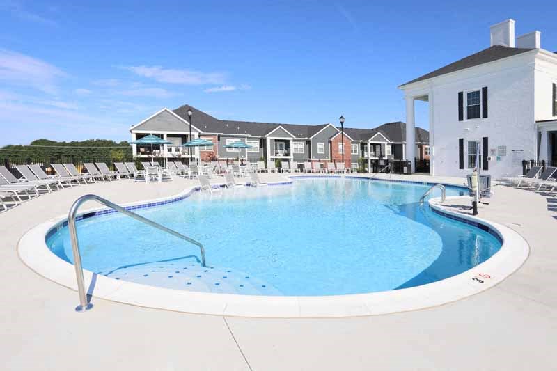 a swimming pool with chairs around it in front of a building