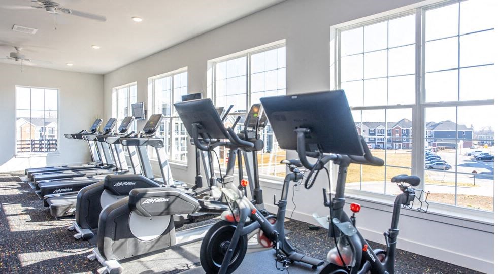 a gym with a row of exercise bikes in front of windows