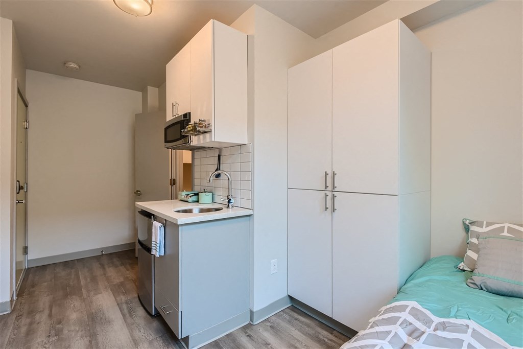 a bedroom with a bed and a refrigerator and a sink