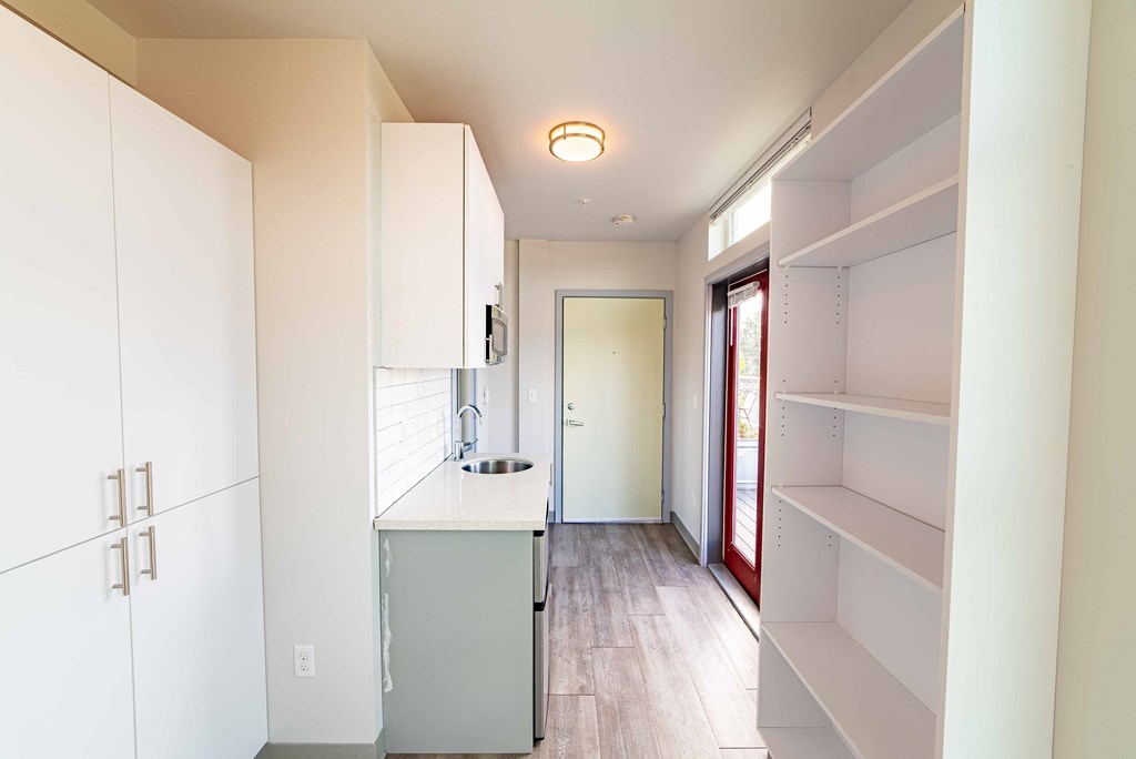 a renovated kitchen with white cabinets and a door to a hallway