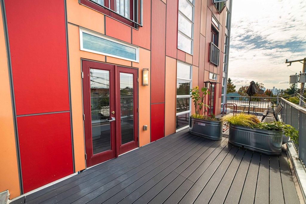 the front porch of a building with red doors and potted plants