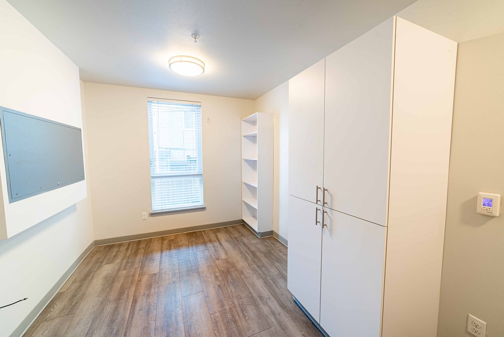 a large white room with wood floors and a white refrigerator