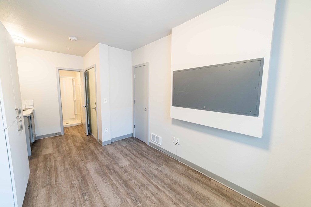 a living room with a tv on the wall and wooden floors