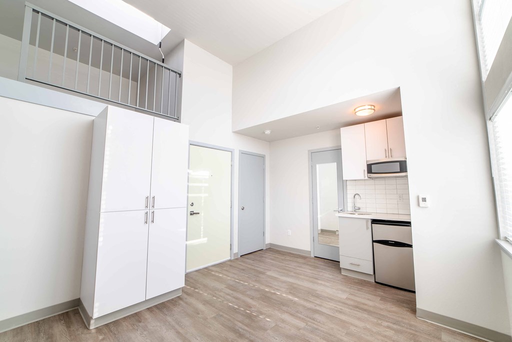 an empty room with a kitchen and a door to a closet