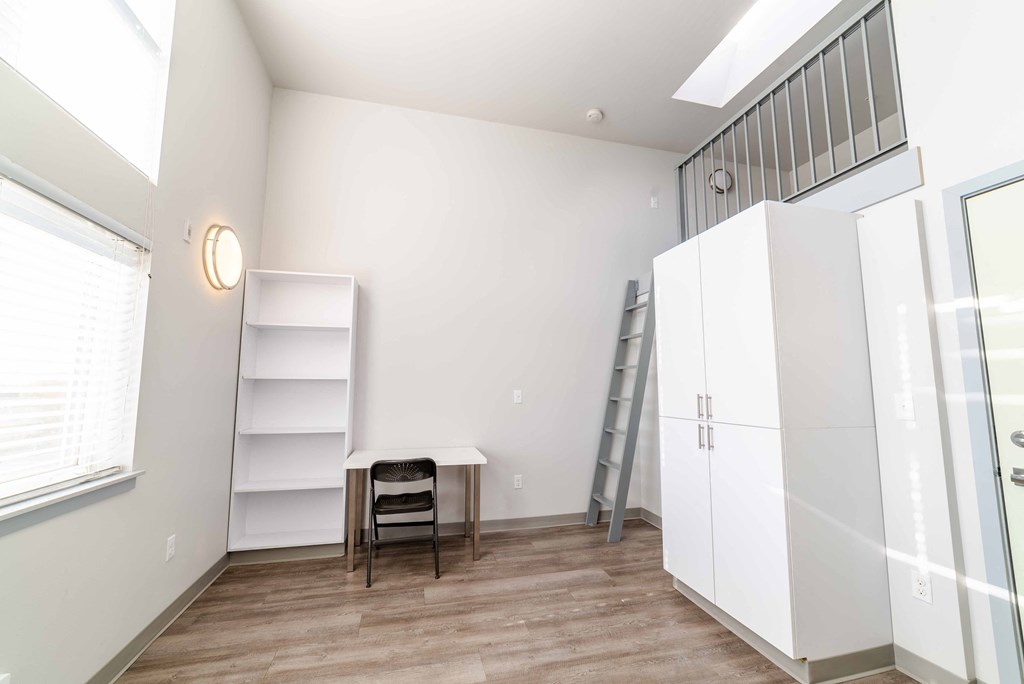 a small room with a wardrobe and a table and a ladder