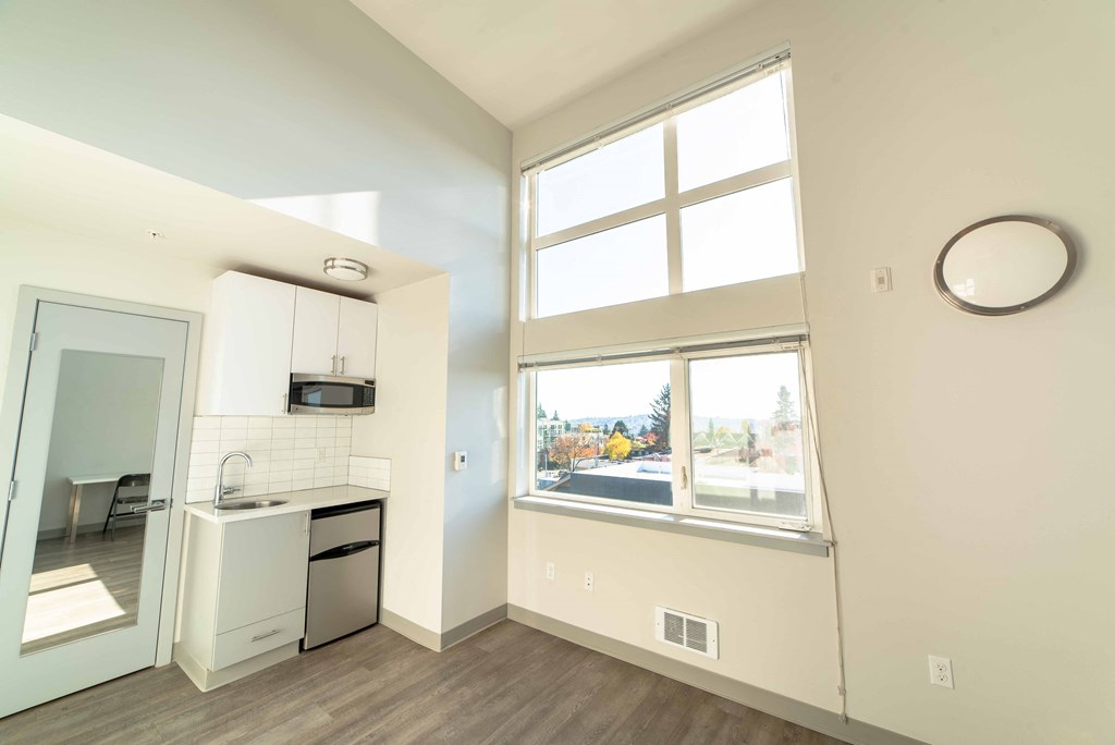 an empty room with a kitchen and a large window