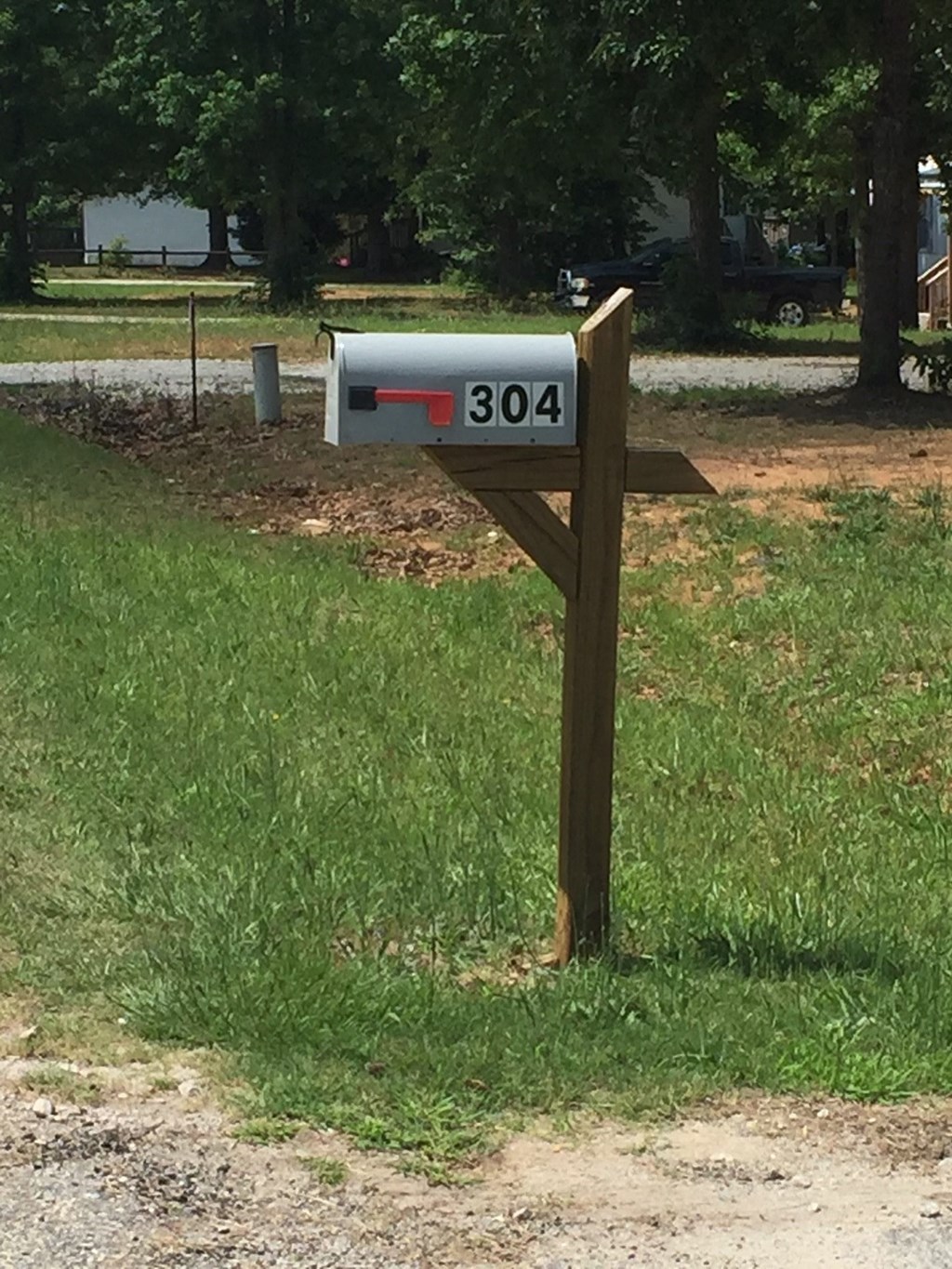A mailbox with the number 304 on it is mounted on a wooden post.