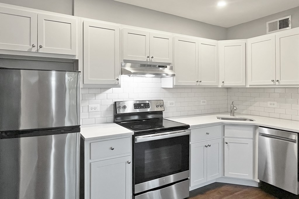A modern kitchen with white cabinets and stainless steel appliances.