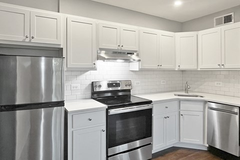 A modern kitchen with white cabinets and stainless steel appliances.